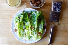 a plate with lettuce, meat and dressing on it next to a cell phone