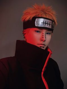 a young man with orange hair and piercings wearing a head band, black jacket and red hoodie