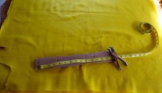 a pair of scissors and measuring tape on a yellow sheet