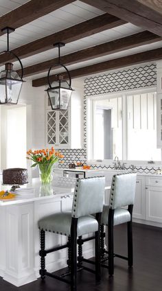 a kitchen with white cabinets and counter tops, two stools at the center of the island