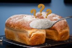 a loaf of bread on a cooling rack with a spoon full of sugar and question marks above it