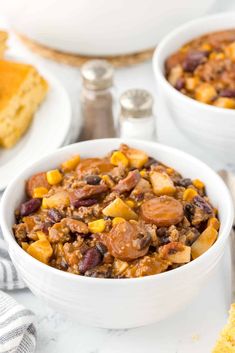 two white bowls filled with chili and cornbread casserole on top of a table