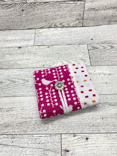 a pink and white dotted notebook sitting on top of a wooden floor