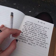 a person holding a pen in their hand and writing on a book with an open page