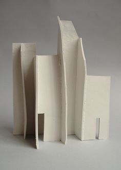 an architectural model is shown on a white surface with no people in the photo, it appears to be made out of paper