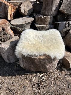 a white sheepskin chair sitting on top of a pile of logs