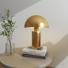 a gold lamp sitting on top of a table next to a vase with a plant