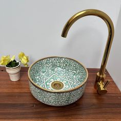 a green and white bowl sink sitting on top of a wooden counter next to a faucet