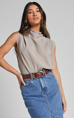 Elevate your outfit with the Arianae Top in Sand. This high neck top is perfect for any occasion, whether it's a party or a day at the office. Made from polyester, this cream-colored top is both fashionable and comfortable. With its sleeveless design and standard fit, it can be easily dressed up or down to suit your style. Add some sophistication to your wardrobe with the Arianae Top - a fashion-forward choice that will make you feel confident and on-trend wherever you go.Product Details:High ne Summer Beige High Neck Top, Chic Beige High Neck Top, Chic Beige Halter Neck Top, Beige High Neck Stretch Top, Fitted Beige Satin Top, Day At The Office, High Neck Top, High Neckline, Feel Confident