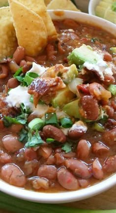 a white bowl filled with beans and tortilla chips on top of a table