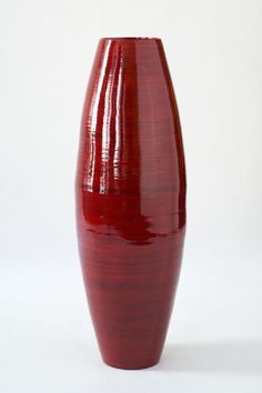 a red vase sitting on top of a white table