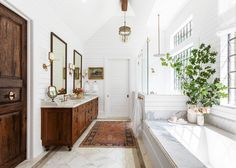 a large bathroom with two sinks, mirrors and plants in vases on the counter