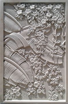 an intricately carved paper art piece with flowers and leaves on the front, in white