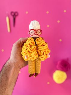 a person holding up a doll made out of knitted material with yarn on it