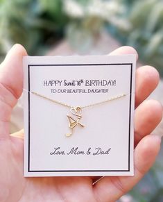 a hand holding a card with a gold necklace on it that says happy birthday to our beautiful daughter