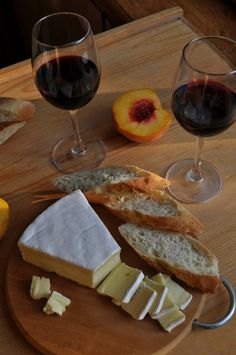 two glasses of wine, bread and cheese on a table