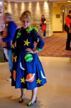 a woman in a blue dress with stars and planets on it, posing for the camera