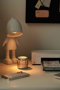 a lamp that is on top of a desk next to a cell phone and printer