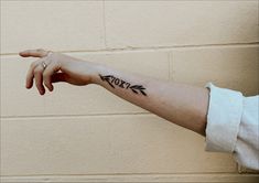 a woman's arm with an arrow tattoo on the left side of her arm