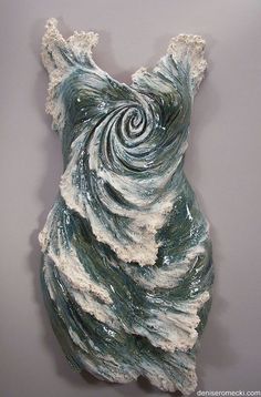 a ceramic sculpture made to look like an ocean wave on a gray background with white and blue swirls