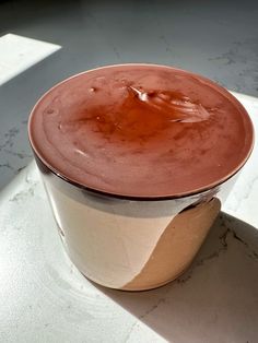 a cup filled with chocolate on top of a white counter next to a shadow from the window