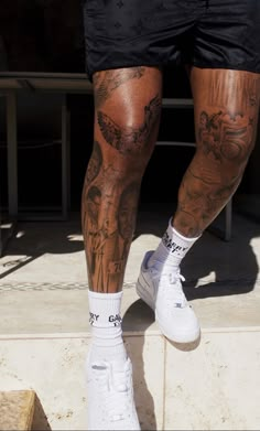 a man with tattoos on his legs and leggings is walking up some steps