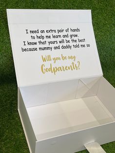 an open box on the grass with some writing in it that says, will you be my godparents?