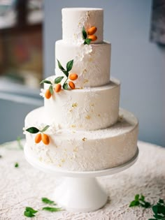 a three tiered white wedding cake with orange berries on top