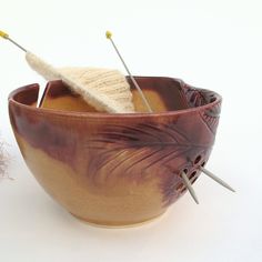 a bowl with needles and yarn in it next to a needle holder on a white surface