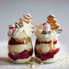 two small jars filled with desserts on top of a white table covered in powdered sugar