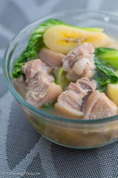 a glass bowl filled with meat and vegetables on top of a cloth covered tablecloth