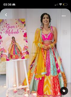 a woman standing next to a sign with candles in front of her and wearing a colorful dress