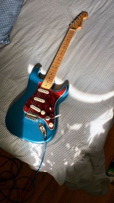 a blue electric guitar sitting on top of a bed