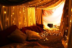 a bed covered in lots of lights next to a window with curtains on the side