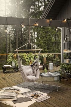 a hammock chair on a deck with lights strung from the ceiling above it