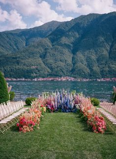 an outdoor ceremony set up with chairs and flowers in front of the water's edge