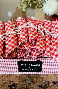 red and white checkered napkins in a box on a counter top with flowers