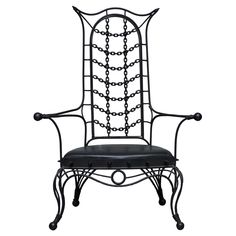 an iron chair with black leather upholstered on the back and arms, in front of