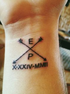 a small wrist tattoo with arrows and the word exxivi - mmi on it