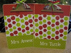 two paper bags with apples on them sitting in front of a christmas tree