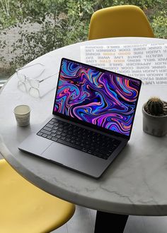 an open laptop computer sitting on top of a table next to a potted plant