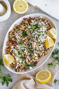 a white bowl filled with food next to sliced lemons and parmesan cheese