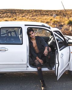 a man sitting in the driver's seat of a white truck with his shirt off