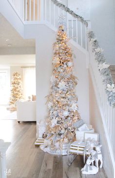 a decorated christmas tree in the corner of a room with stairs and banisters