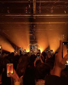 a group of people taking pictures with their cell phones in front of an audience at a concert