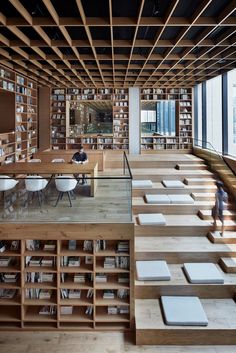 an empty library filled with books and lots of wooden shelves next to large glass windows