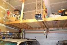 a car is parked in front of a garage with two overhead shelves on the ceiling