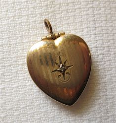 A keepsake heart locket- a small pendant.. A precious little Heart Locket- opens to hold a photo or memento. The front has finely etched lines- with an engraved starburst. Centered is a teeny paste diamond. The locket opens easily and snaps shut securely. marked: inside: 1-20  12K  GF Measures: 14mm at widest and about 14mm tall. {232.27} Locket Vintage, Gold Heart Locket, Heart Locket, Small Pendant, Husband Love, Locket Necklace, Gold Heart, Heart Of Gold, Locket