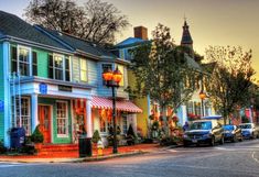 a row of colorful houses with cars parked on the street