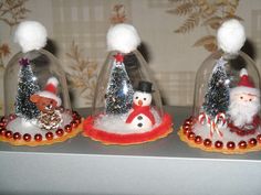 three christmas decorations under glass domes on a shelf